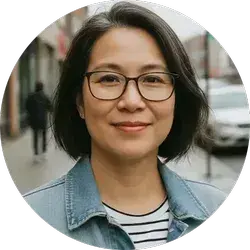 Headshot of Angela, a smiling woman with glasses and a denim jacket